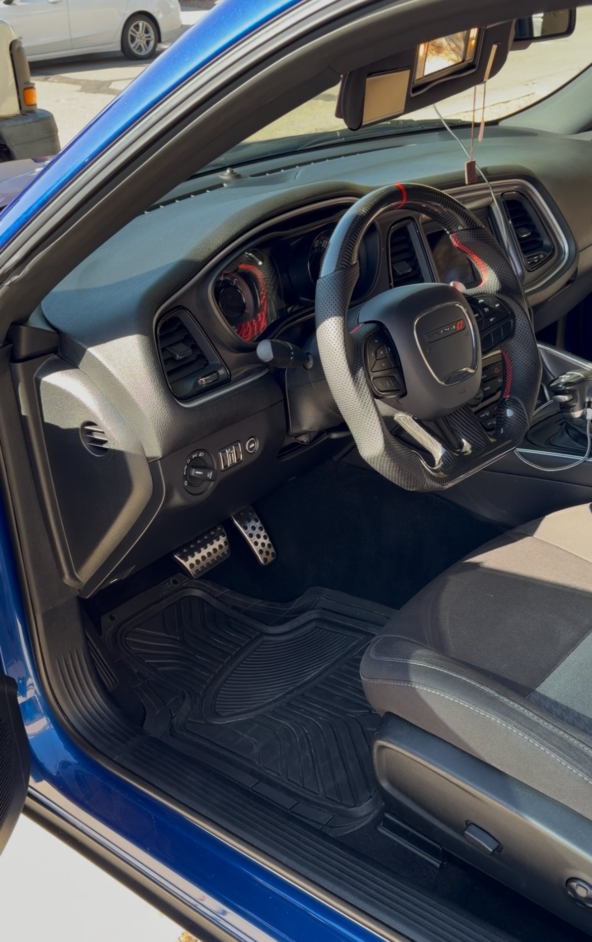 Interior of a blue sports car showing steering wheel, dashboard, and black and gray seats with open drivers door